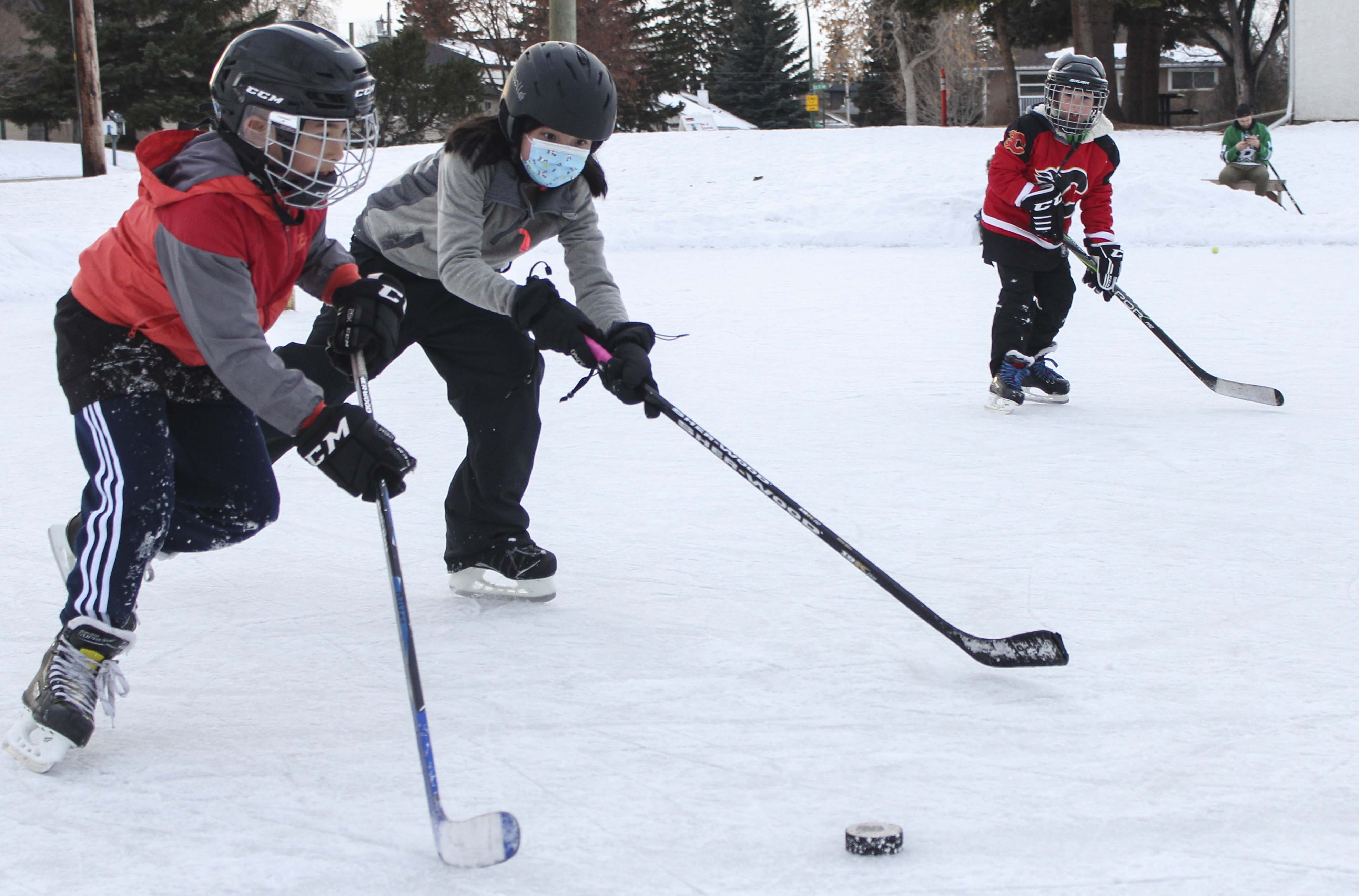 Children are playing ice hockey on the Highland Park community rink in Calgary on Sunday, Jan. 31, 2021. The January weather has been pleasantly warm for the families to enjoy some outdoor winter activities during the pandemic. (Photo by Meng Wei/The Press). (Photo by Meng Wei/The Press)